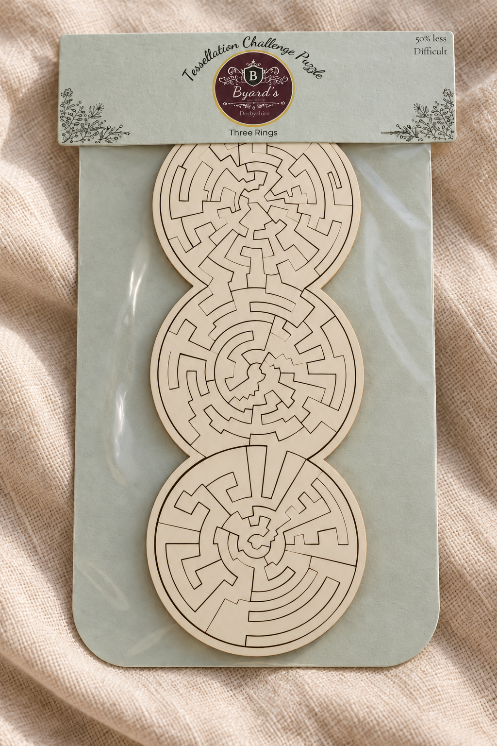 Close-up of the Three Rings easier wooden puzzle on linen, showing its white face and precisely cut interlocking shapes.