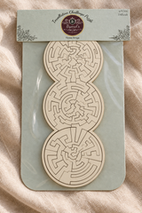 Close-up of the Three Rings easier wooden puzzle on linen, showing its white face and precisely cut interlocking shapes.