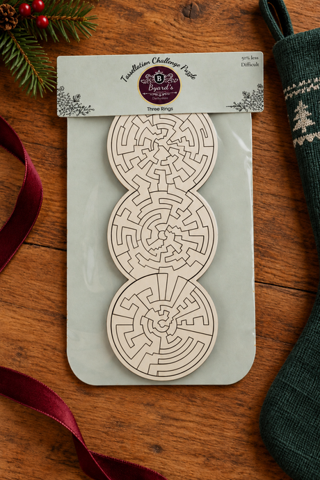 Three Rings easier wooden puzzle with white pieces, styled on oak beside a green Christmas stocking, ribbon and fir sprig.