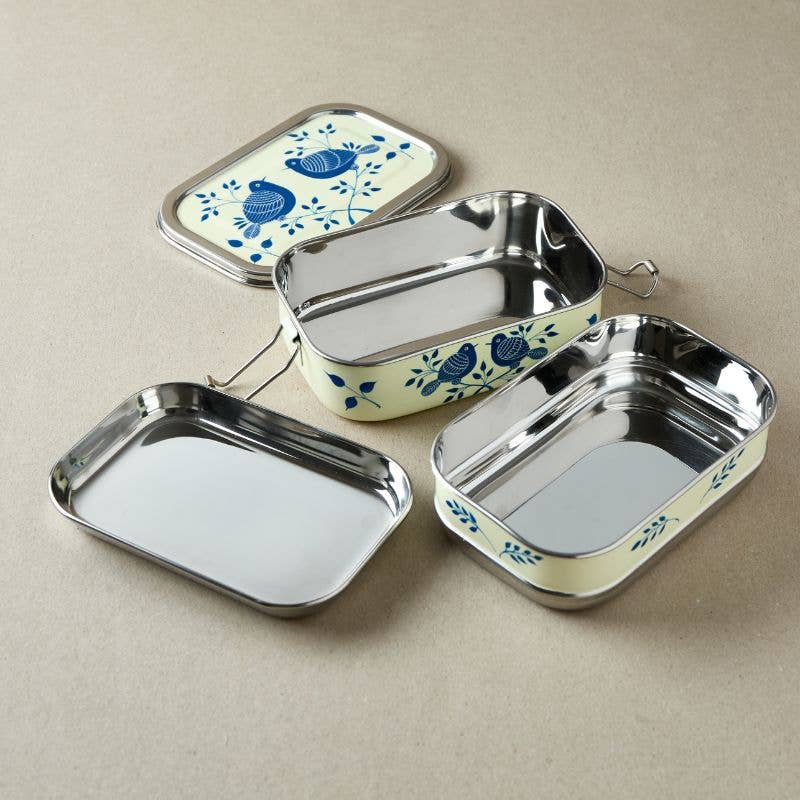 Set of stainless steel lunch boxes with floral designs on a beige background