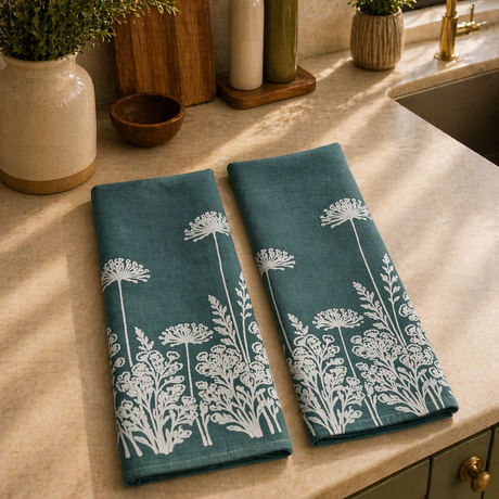 Linen tea towels with white floral patterns on a kitchen counter.