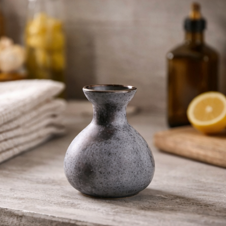 Gray ceramic vase on a wooden surface with a cozy living room background.