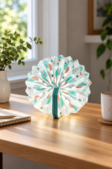 Turquoise Geometric Velvet Accordion Lamp on a sunlit oak desk beside a notebook and ceramic cup, with cool white light through the patterned folds.