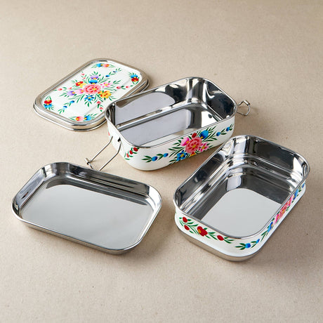tiffin tin Set of three metal lunch boxes with floral designs on a beige background