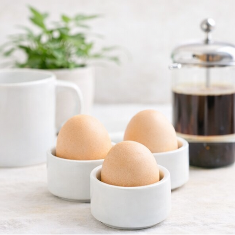 eggs in white cups with coffee.
