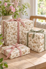 Three gifts wrapped in vintage woodland fawn paper with pink and sage ribbon on a sunny oak table.