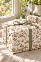 Close-up of a woodland fawn gift parcel with sage ribbon and soft botanical illustrations.