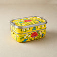 Stackable yellow tiffin tin containers with floral patterns on a beige background